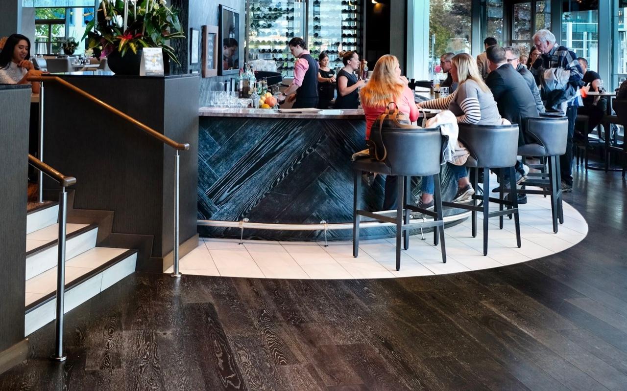 A restaurant setting with a dark wood or wood composite floor as a focal point.